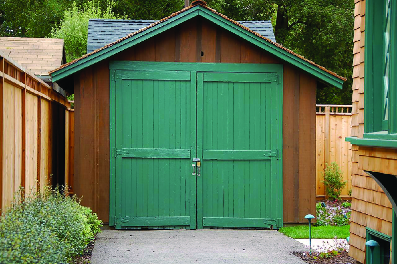 This image shows a small wooden garage in a backyard.
